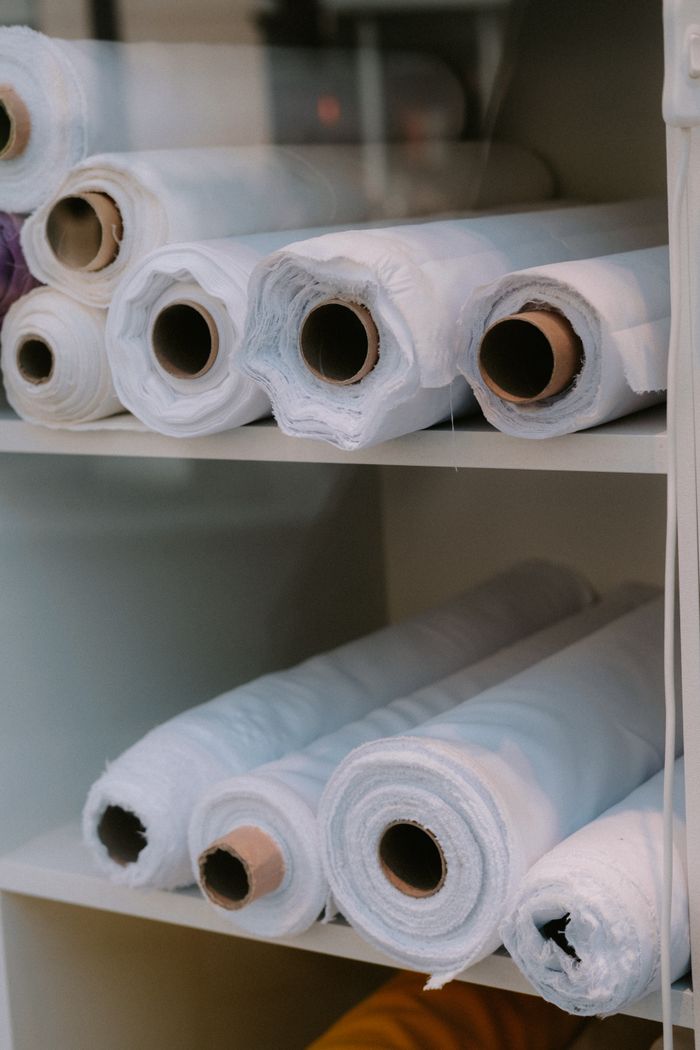 White rolls of fabric stacked on shelves, ideal for textile and fashion projects.