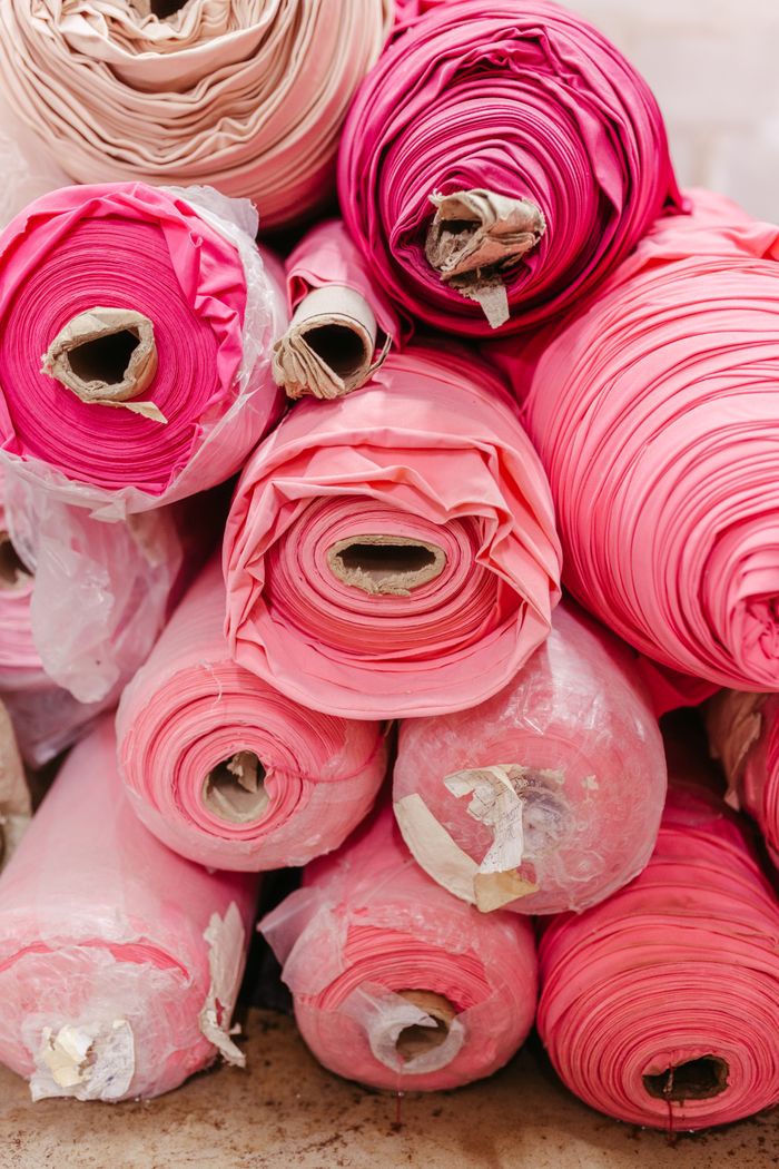 A close-up of vibrant pink fabric rolls stacked in an organized manner.