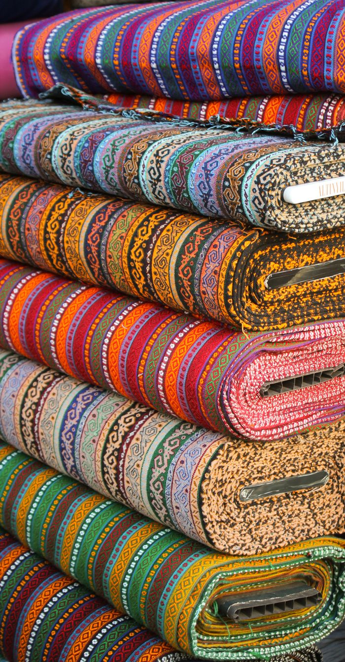 Vibrant stacked textiles with intricate ethnic patterns, showcasing diverse colors.